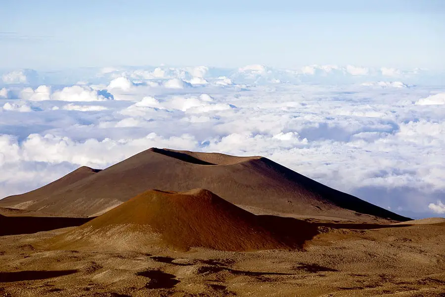 Brown cinder cones on Mauna Kea Volcano on the island of Hawaii, protruding above the clouds