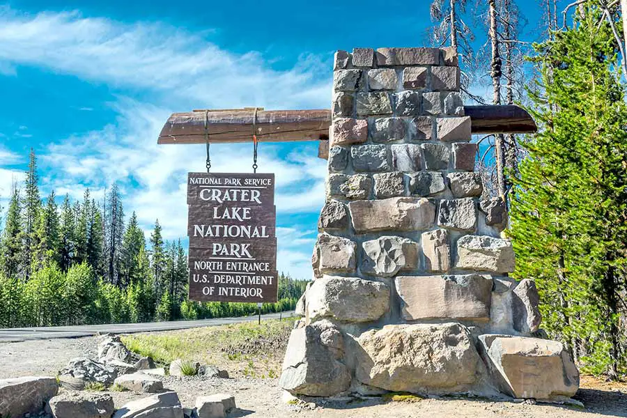Entrance sign to national park on log and boulder pedestal