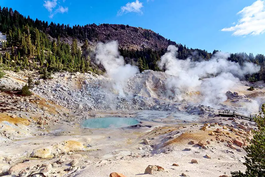 Steam rising from hot springs and fumaroles in rugged mountains