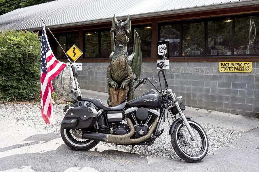 Black Harley Davidson motorcycle with American flag in front of dragon statue