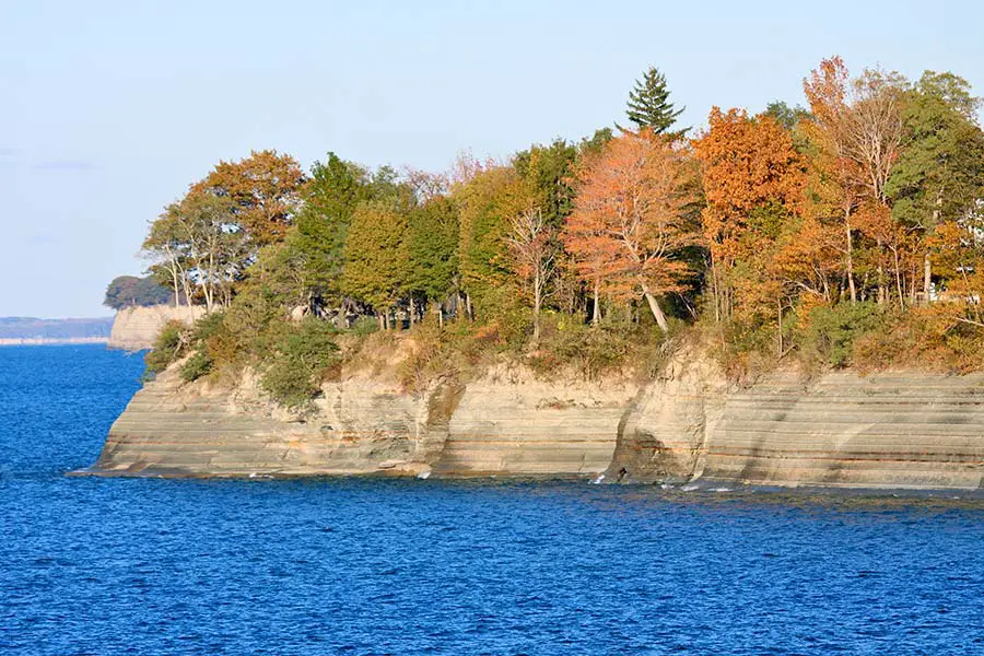 Rocky tree covered cliffs line the shore of large lake