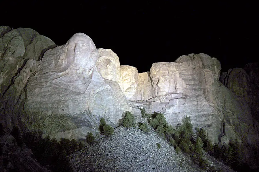 Nighttime view of Presidential sculptures illuminated by spotlights