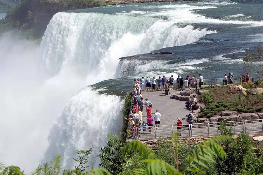Tourists on observation deck viewing massive waterfall