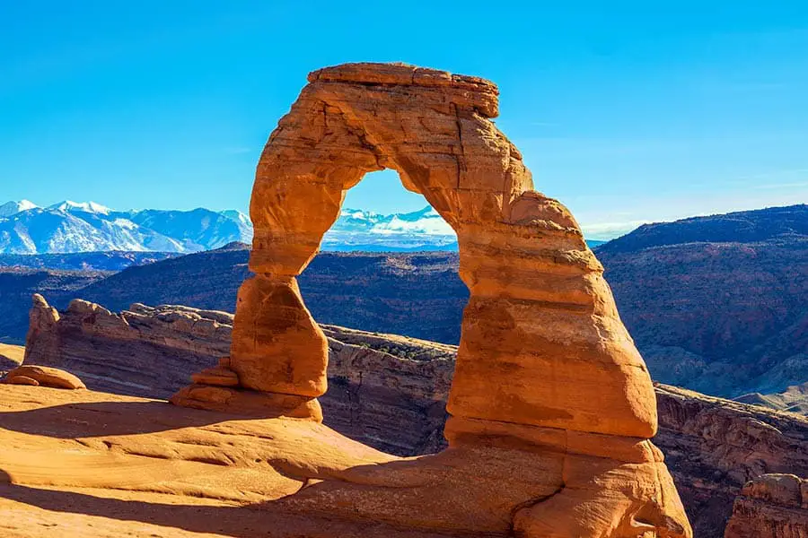 Stone arch framed by blue sky and rock formations in Utah