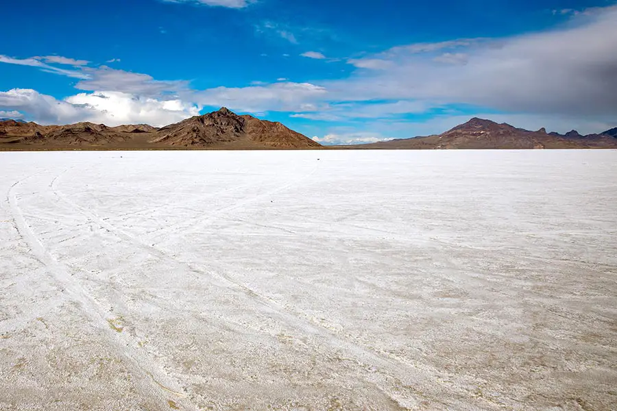 Tire tracks in salt flats with mountains on the horizon