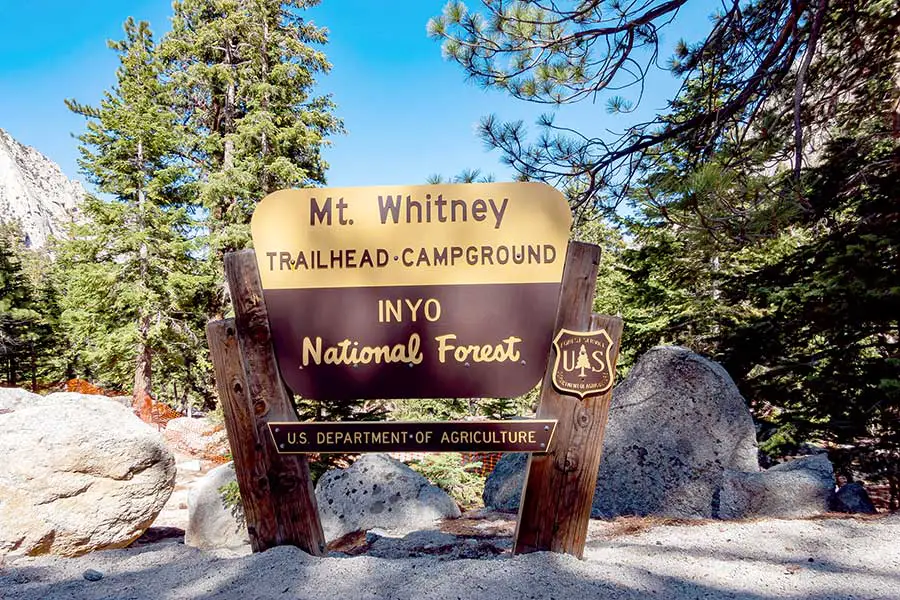 Mt. Whitney trailhead sign, in the Inyo National Forest surrounded by boulders and trees