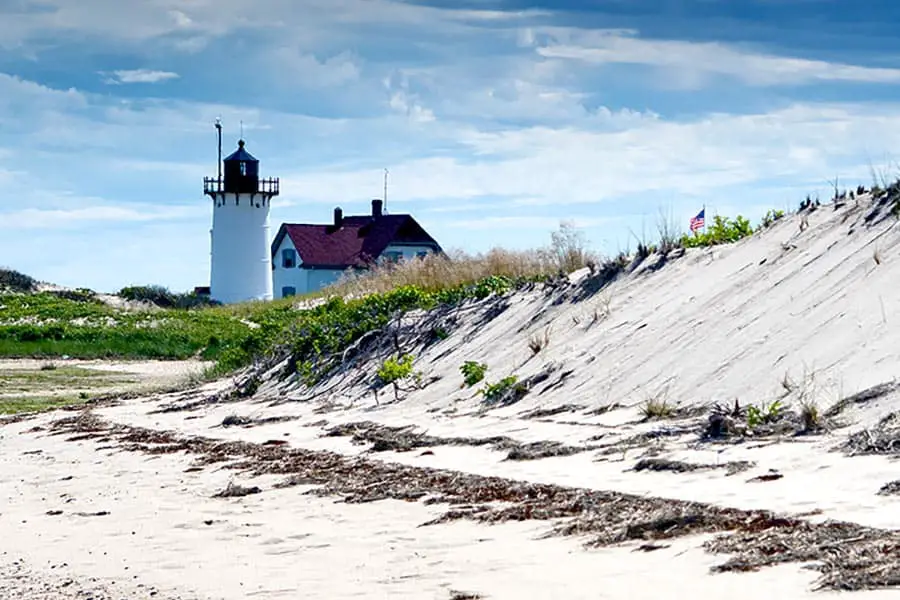 White lighthouse with lightkeepers home surrounded by sand dunes