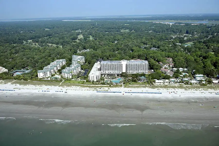 Aerial view of beach with resort hotels, green trees in the background