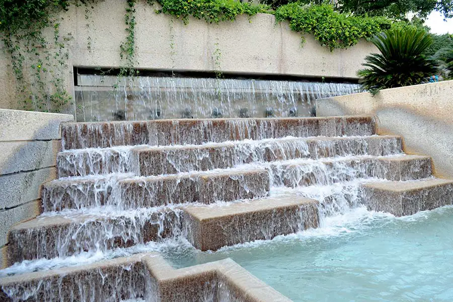 Water cascades down concrete staircase into pool