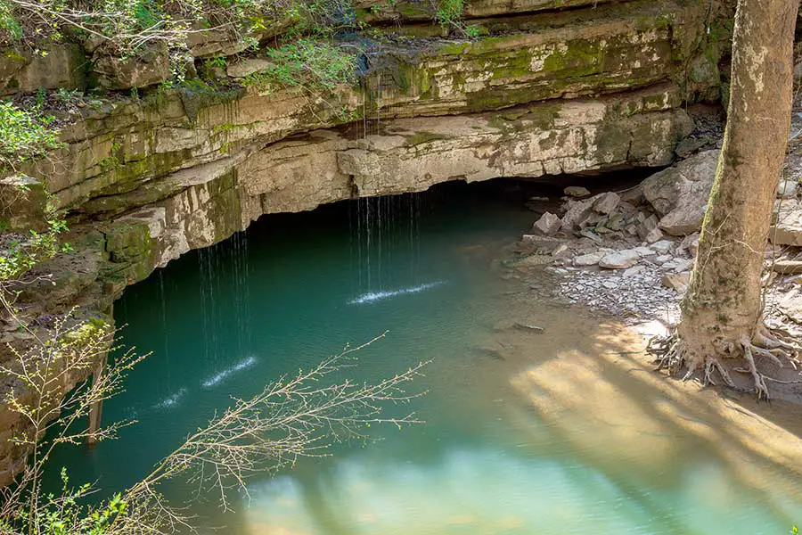Water flowing into cave under horizontal layers of rock